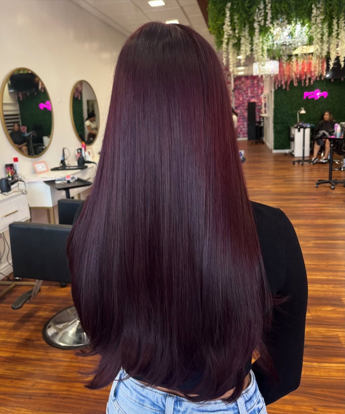 5 No Bleach London Vivid Berry Hair Color Ideas 1 Long straight berry-purple hair shown from behind in a modern hair salon setting.