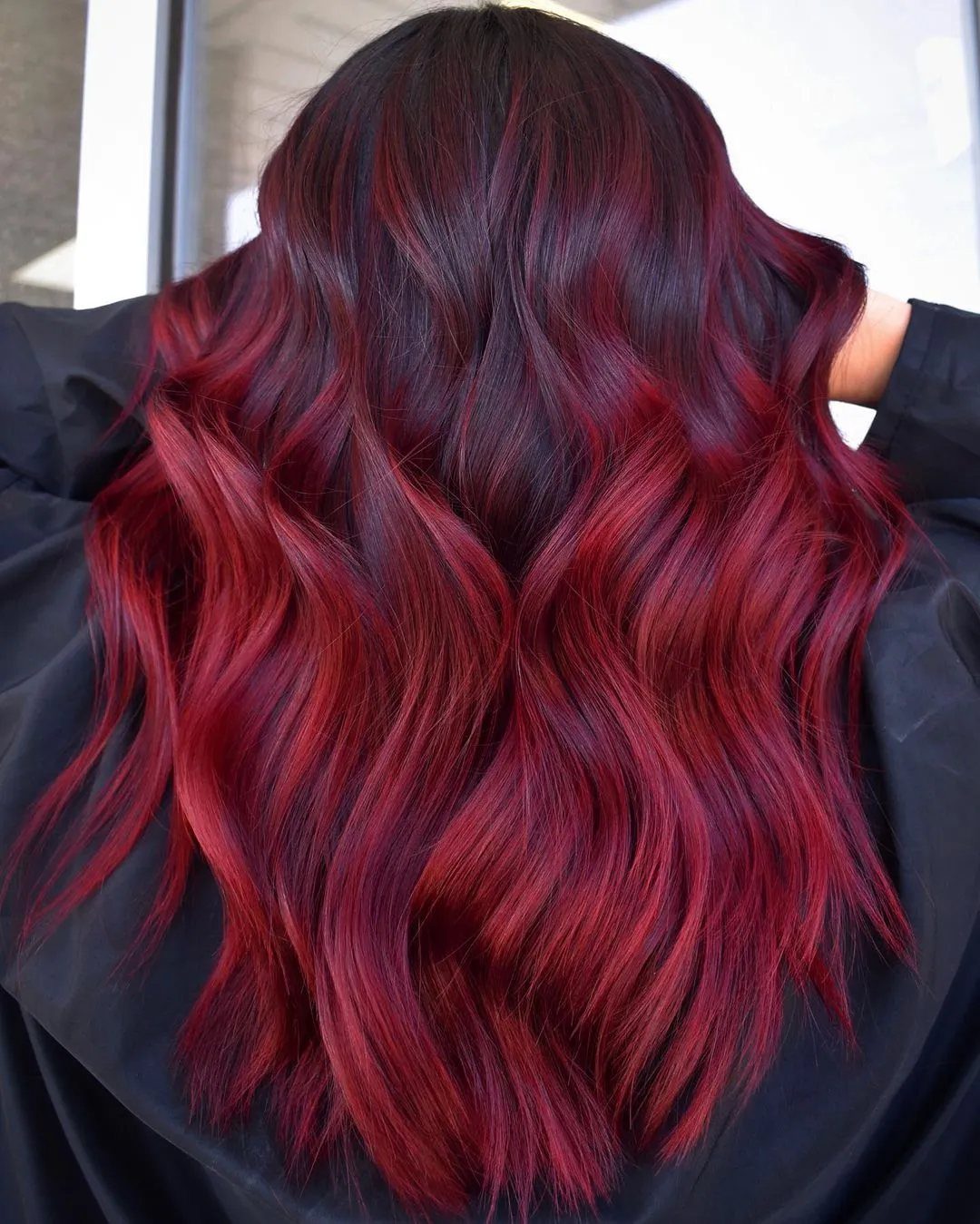 Oxblood Hair Color Ideas: 5 Looks for Every Length 2 Long wavy hair with deep oxblood red roots transitioning to lighter red ends.