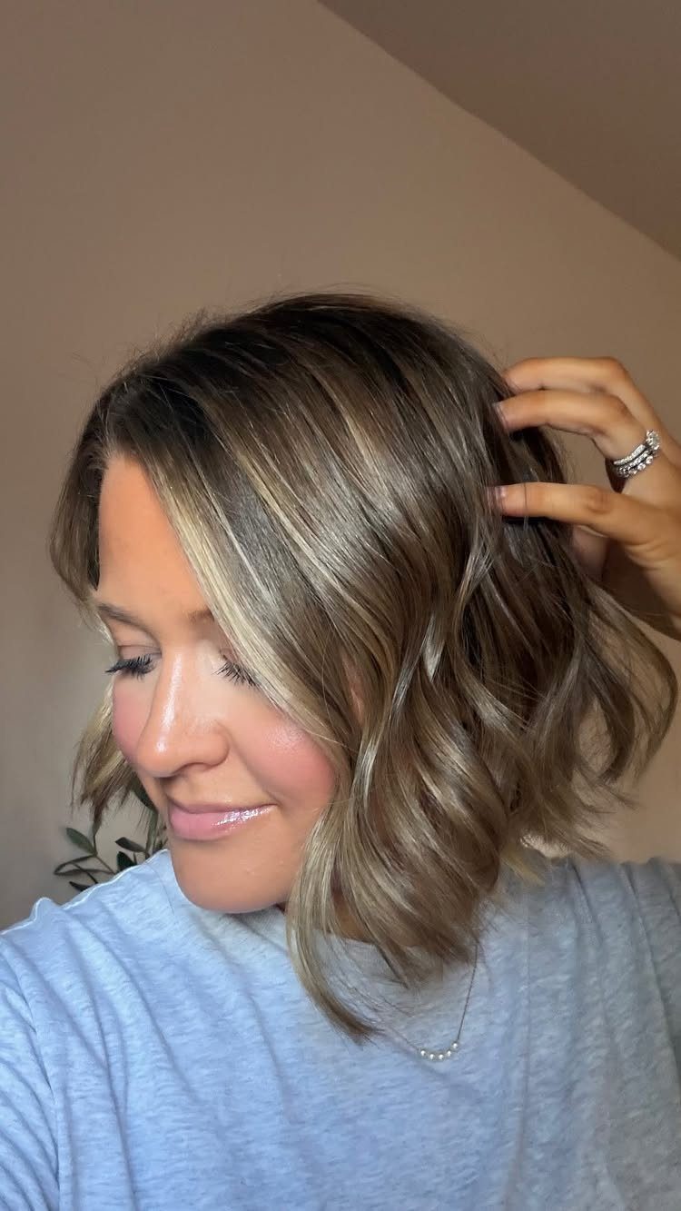 Woman with a bronde layered bob haircut and wavy blonde highlights.
