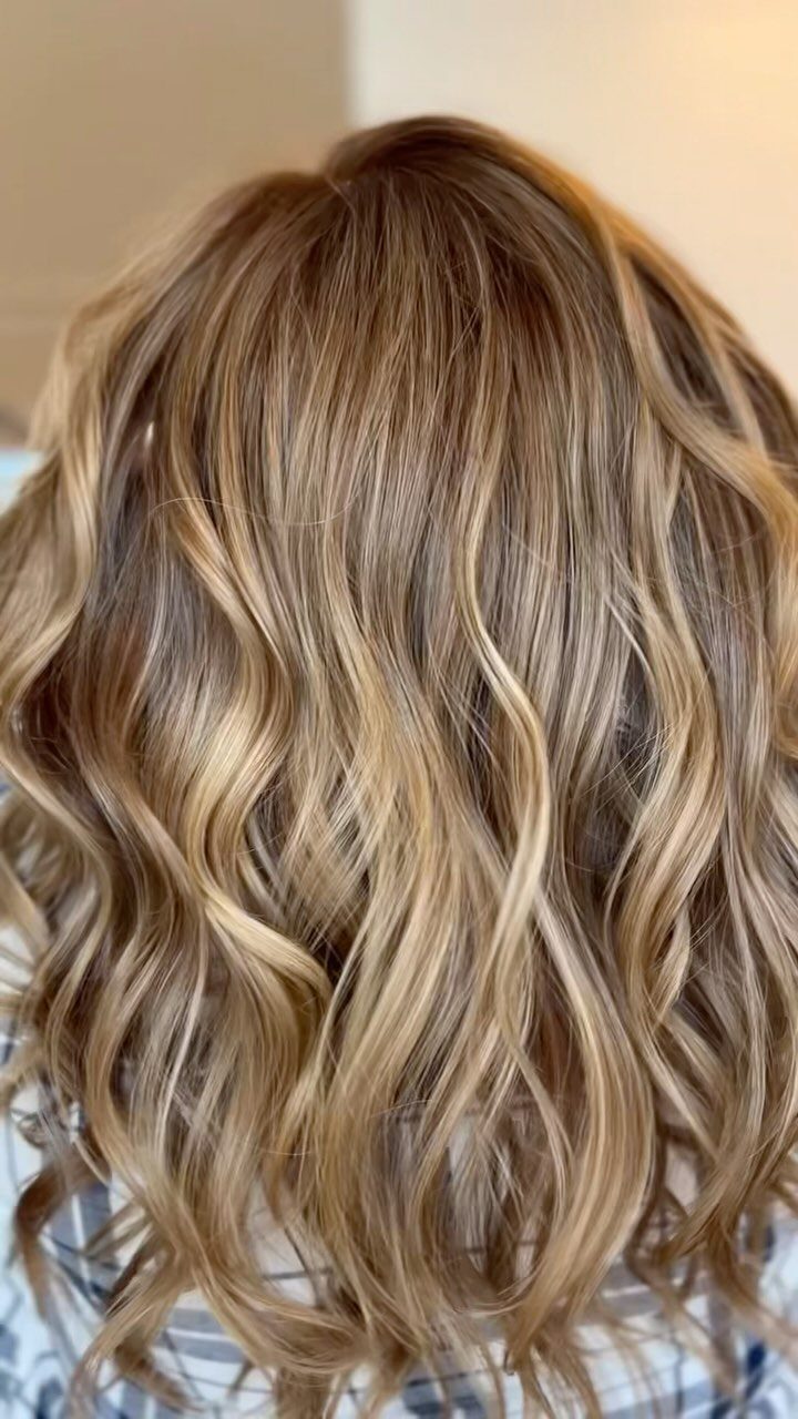Wavy caramel blonde hair with honey highlights seen from the back.
