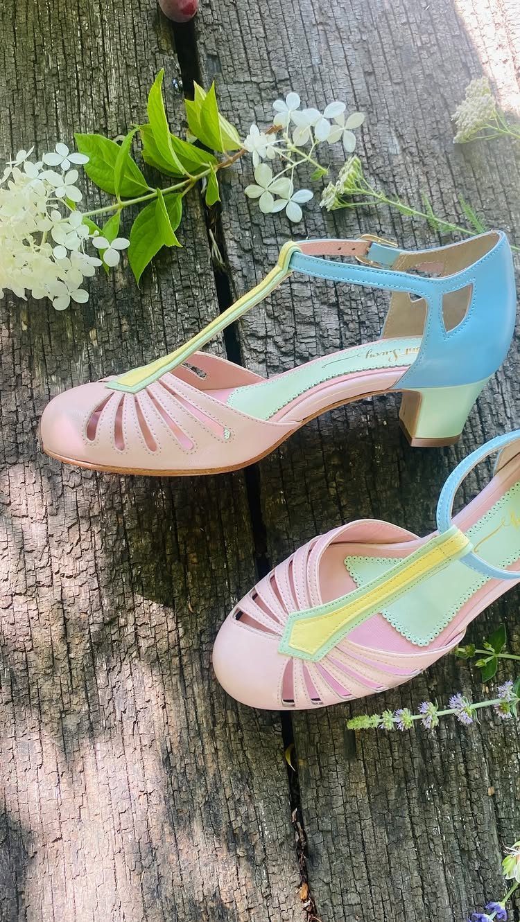 Pink vintage T-strap heels with blue and yellow accents on a wooden deck