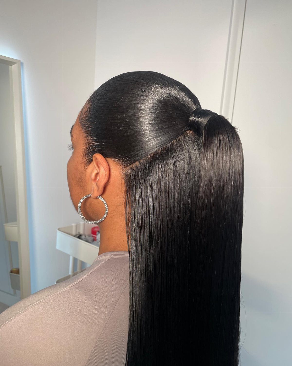 Woman with long sleek black hair styled in a polished low ponytail.