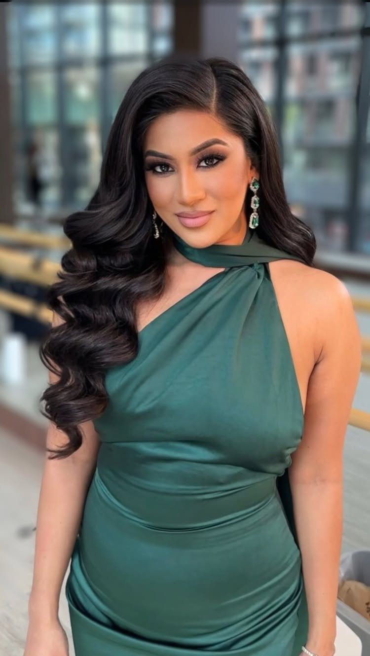 Woman with long dark hair in soft Hollywood waves and a green dress