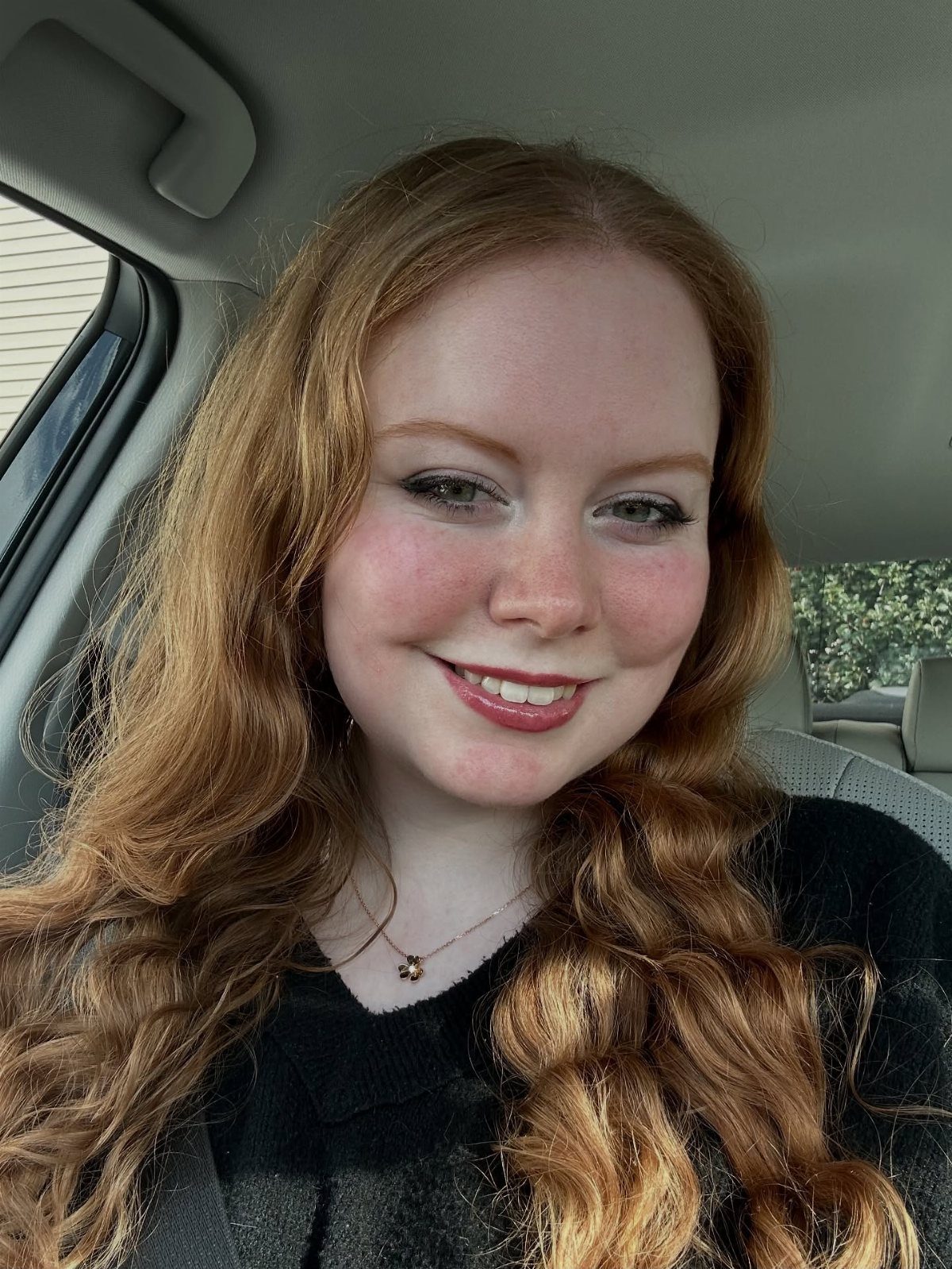 13 Red Undertones Hair Ideas, From Copper to Burgundy 9 Woman with long wavy ginger hair and freckles smiling inside a car