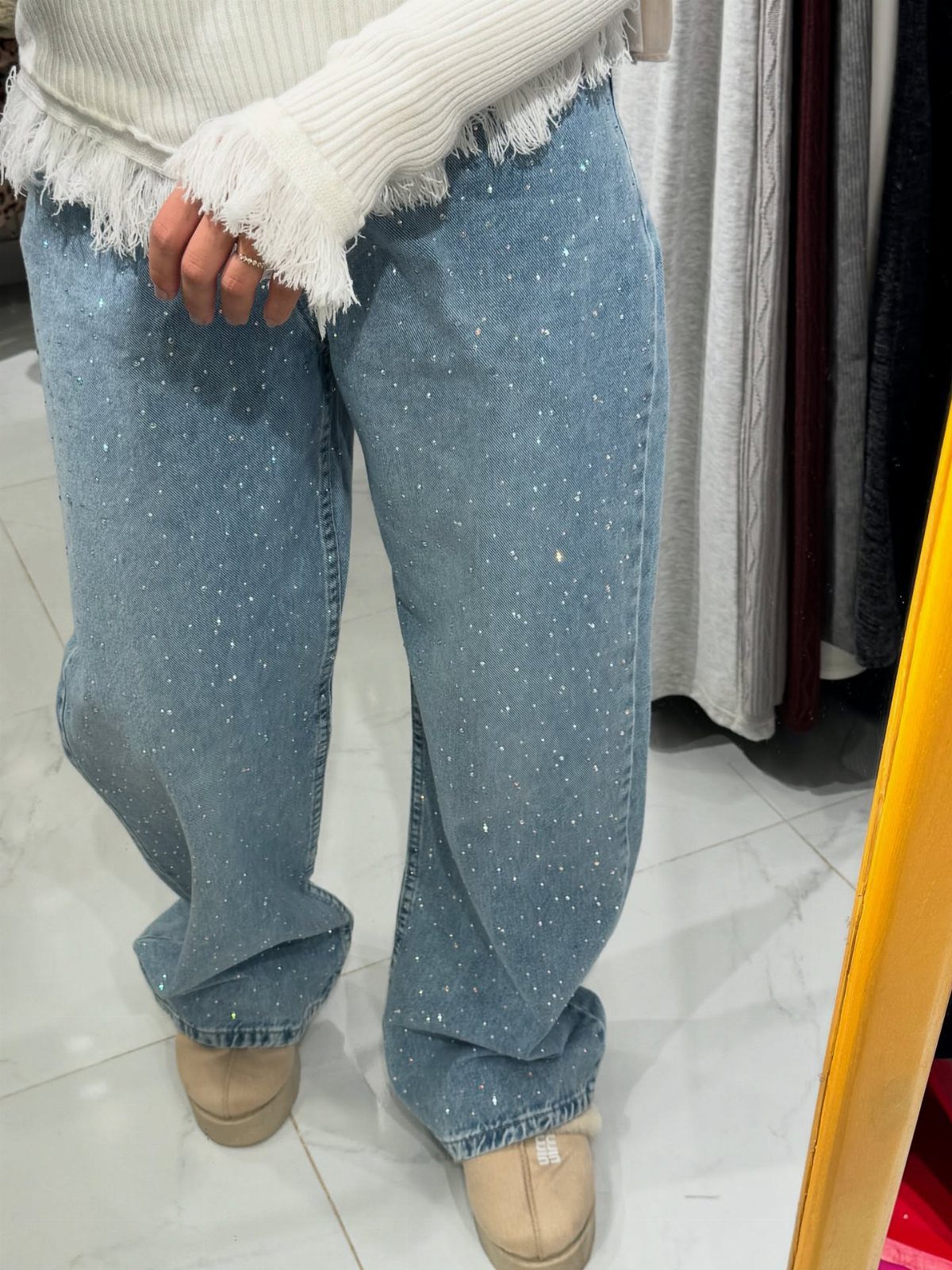 Light blue rhinestone jeans paired with a white chunky knit fringed sweater.