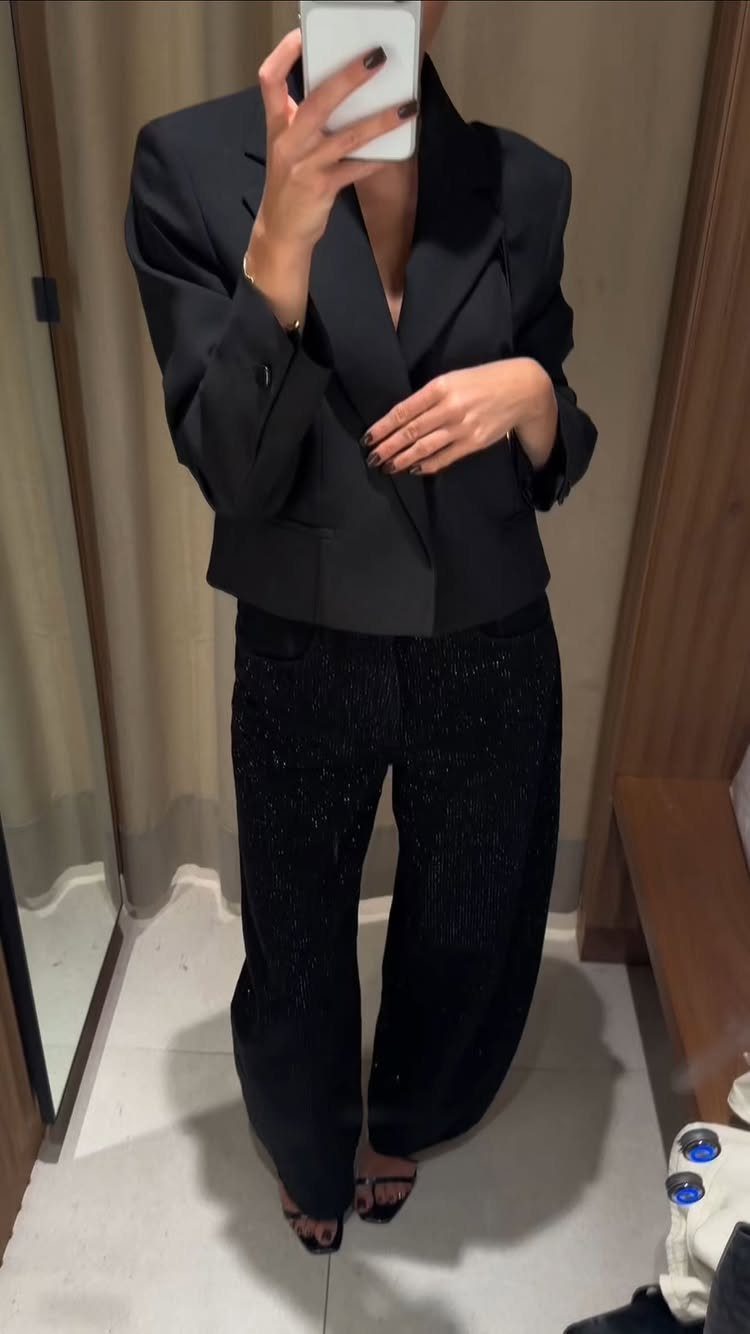 Person wearing a black blazer and wide-leg black rhinestone embellished jeans.