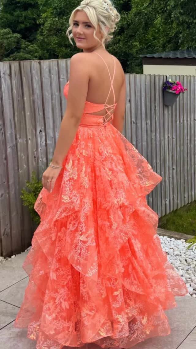 8 Rio Prom Dress Ideas for Florals, Sequins and Mermaid Cuts 7 Woman wearing a coral red tiered gown with a lace-up back outdoors.