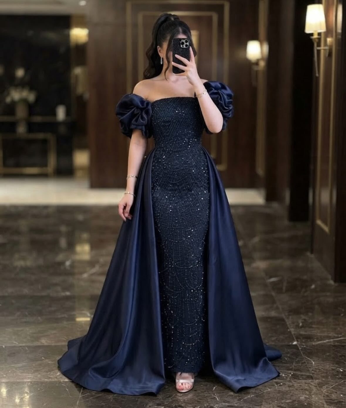 8 Rio Prom Dress Ideas for Florals, Sequins and Mermaid Cuts 6 Woman in a navy blue sequined mermaid gown with a matching overskirt.