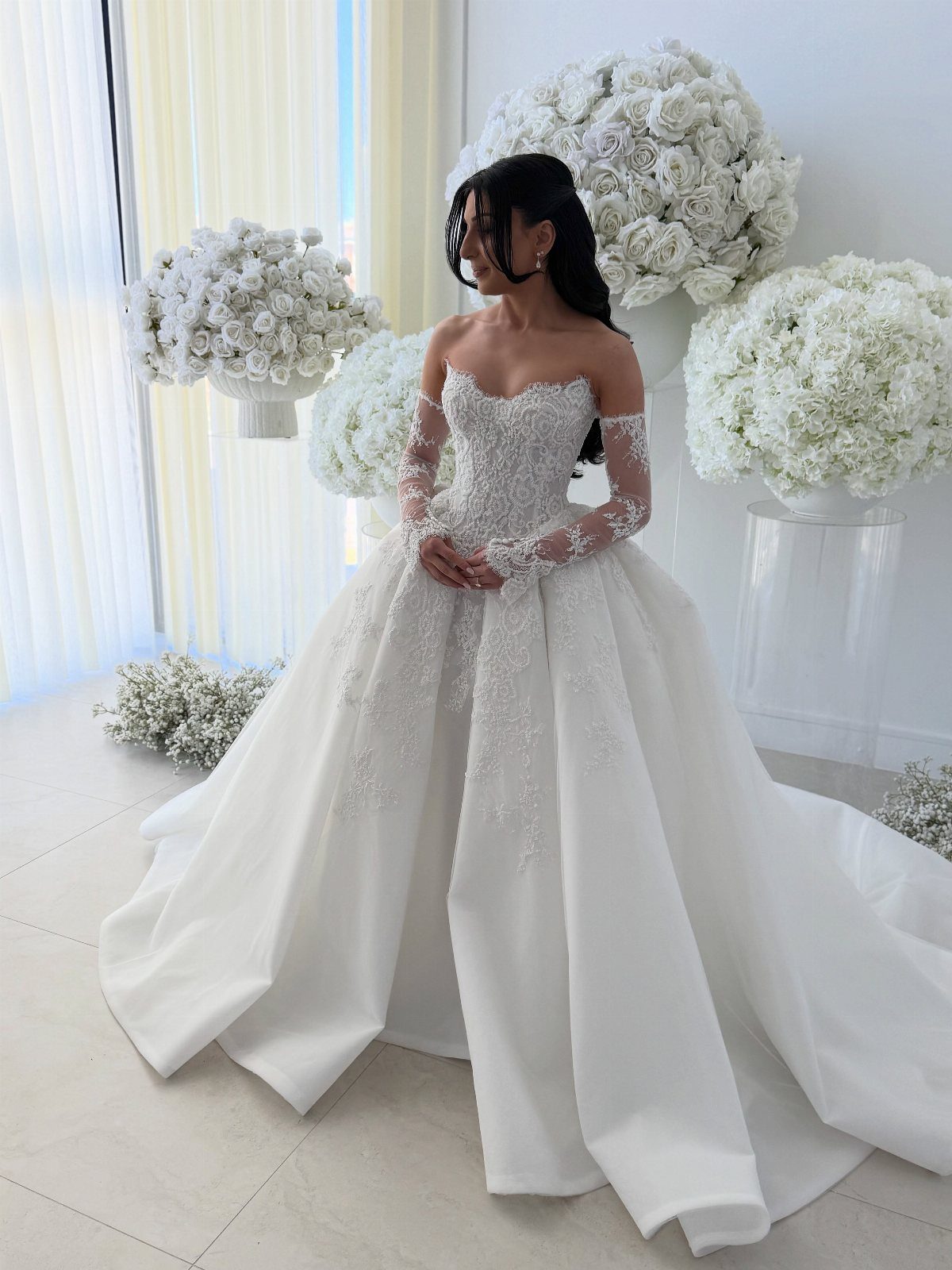 Woman in a white A-line wedding dress with lace details and white roses.