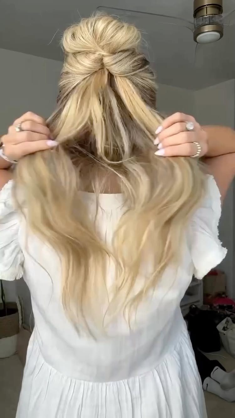 8 Simple Half Up Hairstyles for Every Occasion 1 Blonde hair styled in a half-up top knot bun on a woman.