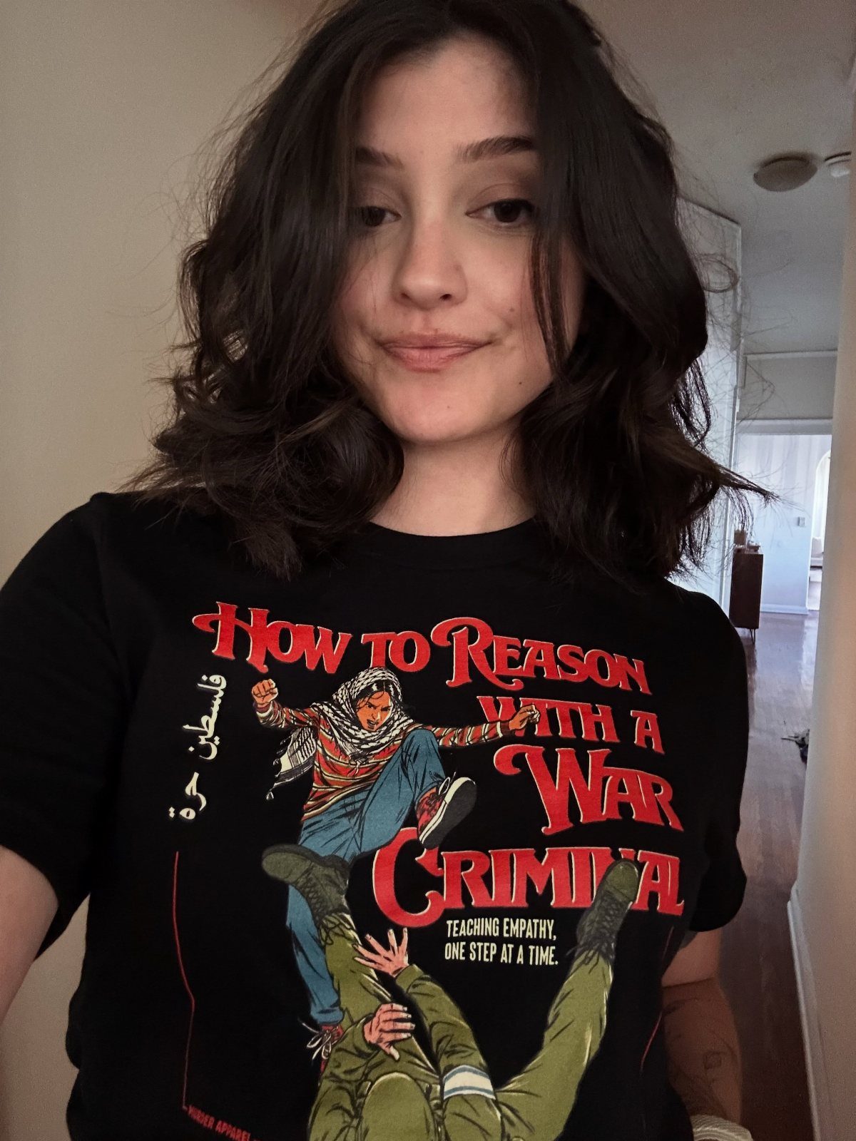 Woman wearing a black t-shirt with a political graphic and red text.