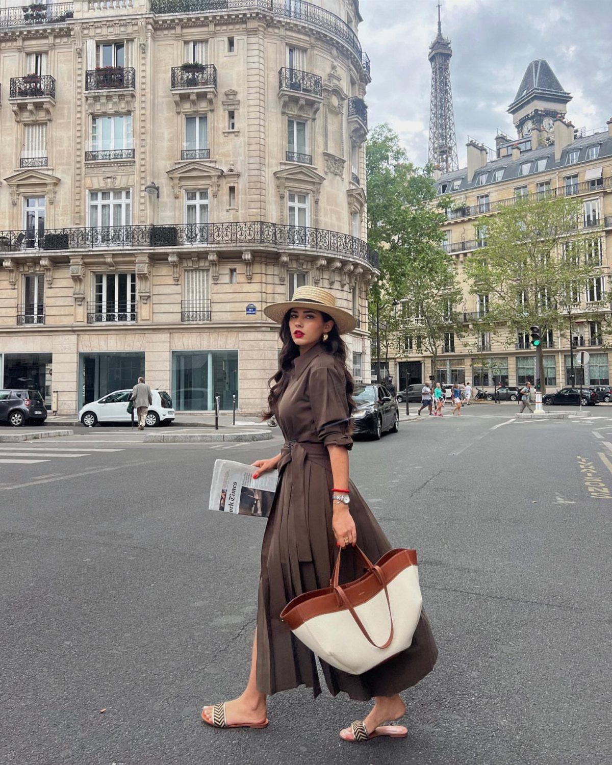 Woman in a brown midi dress and straw hat walking in Paris