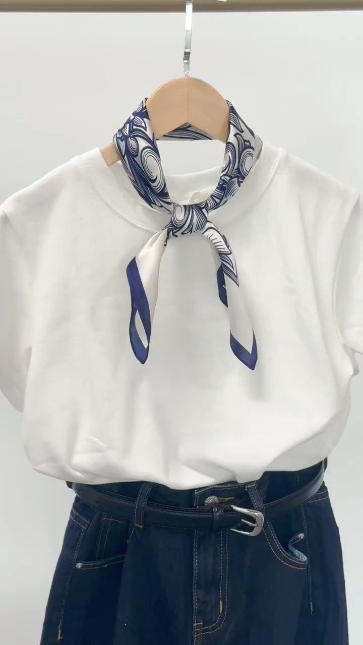 White t-shirt and dark jeans with a blue patterned silk scarf tied around neck