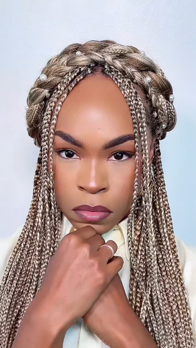 Woman with blonde box braids styled into a pearl-accented braided crown updo.
