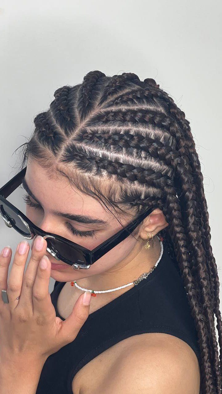 Woman with cornrows and long box braids wearing black sunglasses and white necklace.