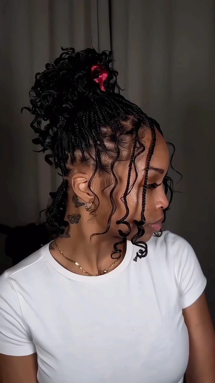 Woman with black box braids styled in a high bun with curly tendrils.