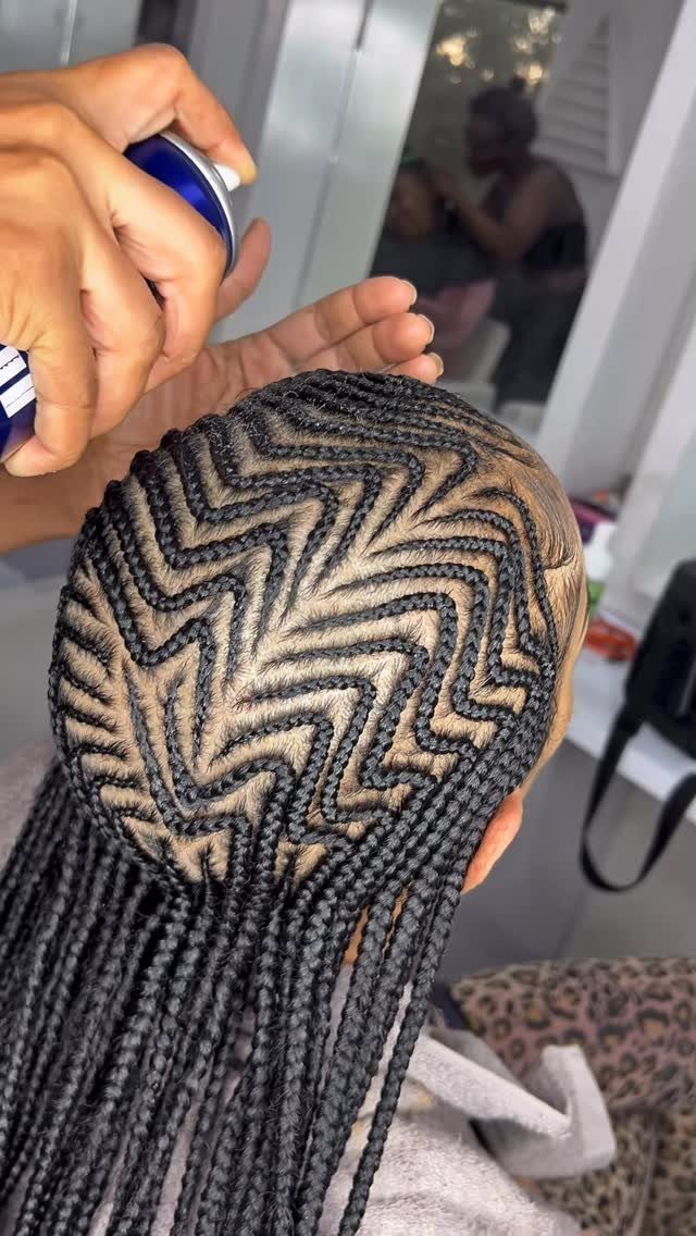 Black box braids with a zigzag parting pattern being sprayed with hair product.