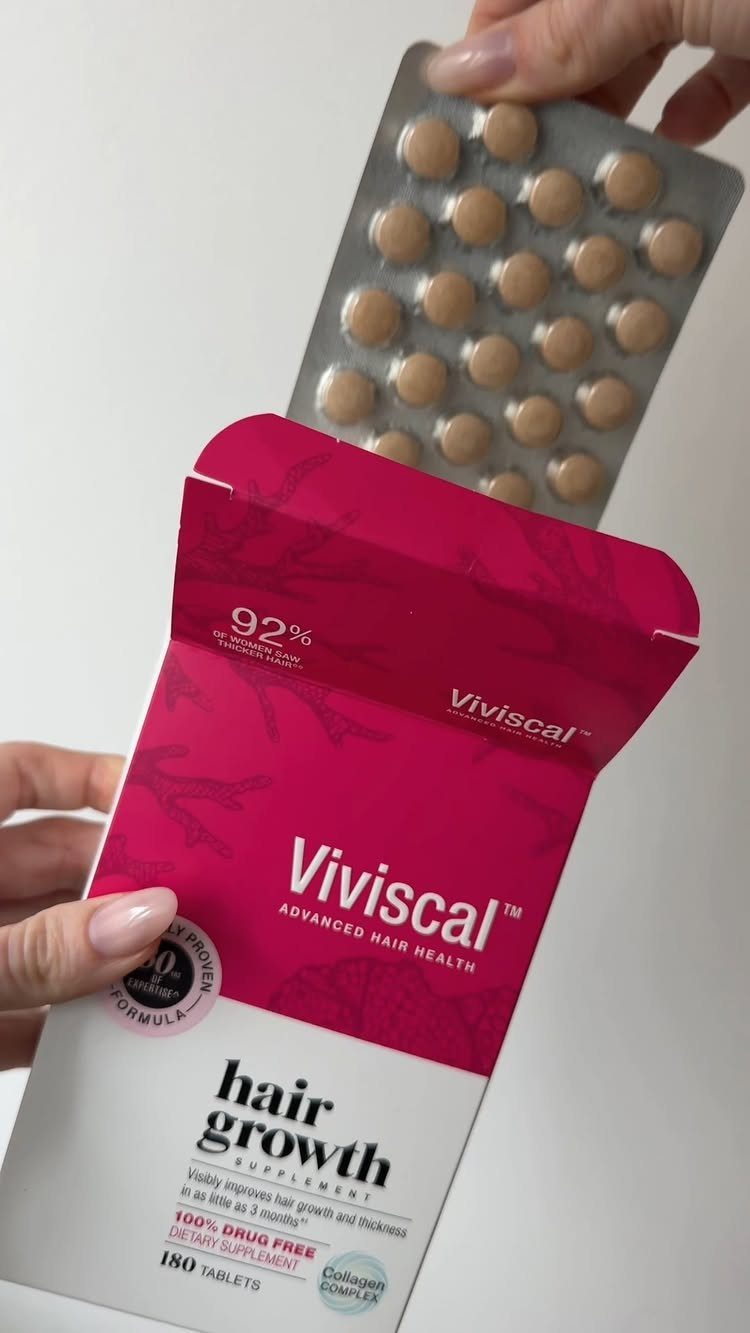 Viviscal hair growth supplement box and blister pack of brown tablets held by hands.