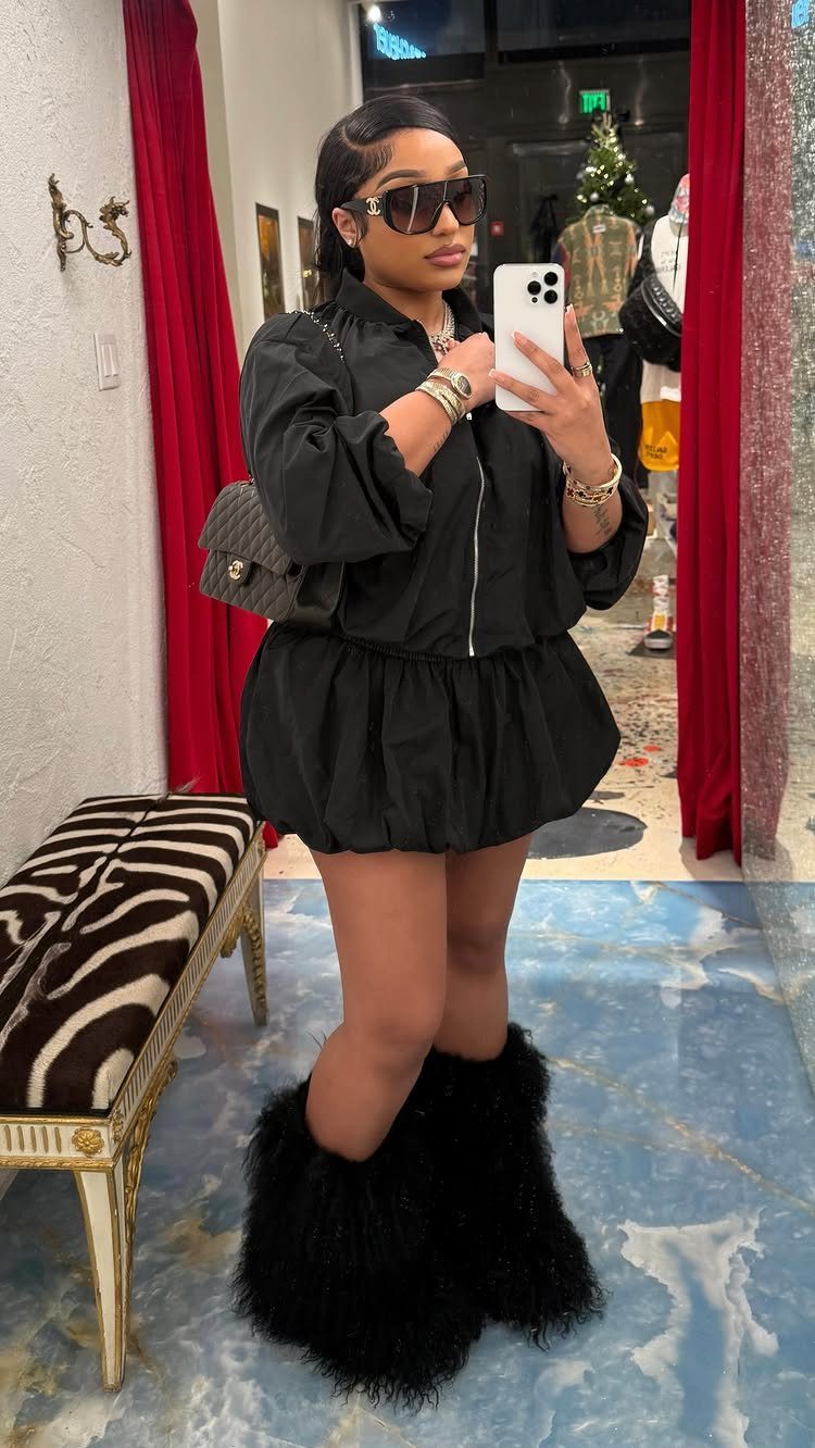 Woman wearing a black track jacket and bubble mini skirt with fluffy boots.