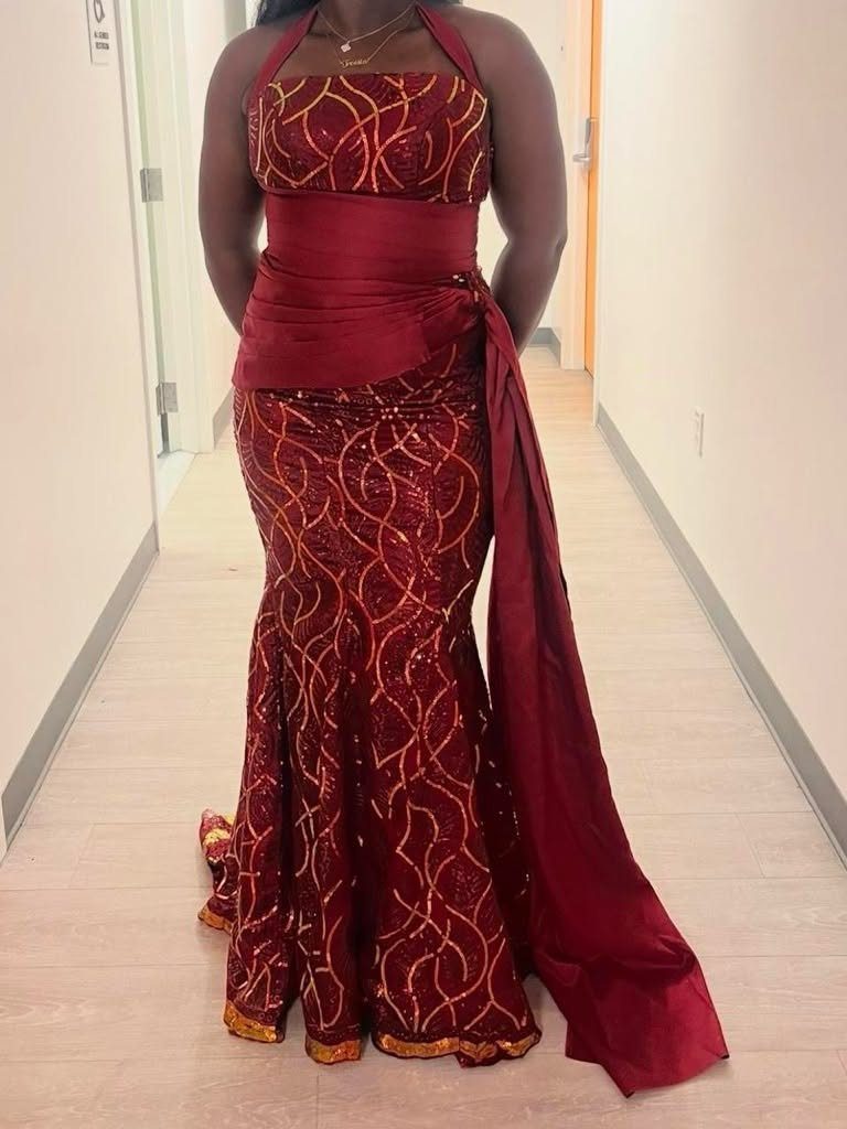 Burgundy sequined mermaid gown with gold swirl patterns and a long satin sash.