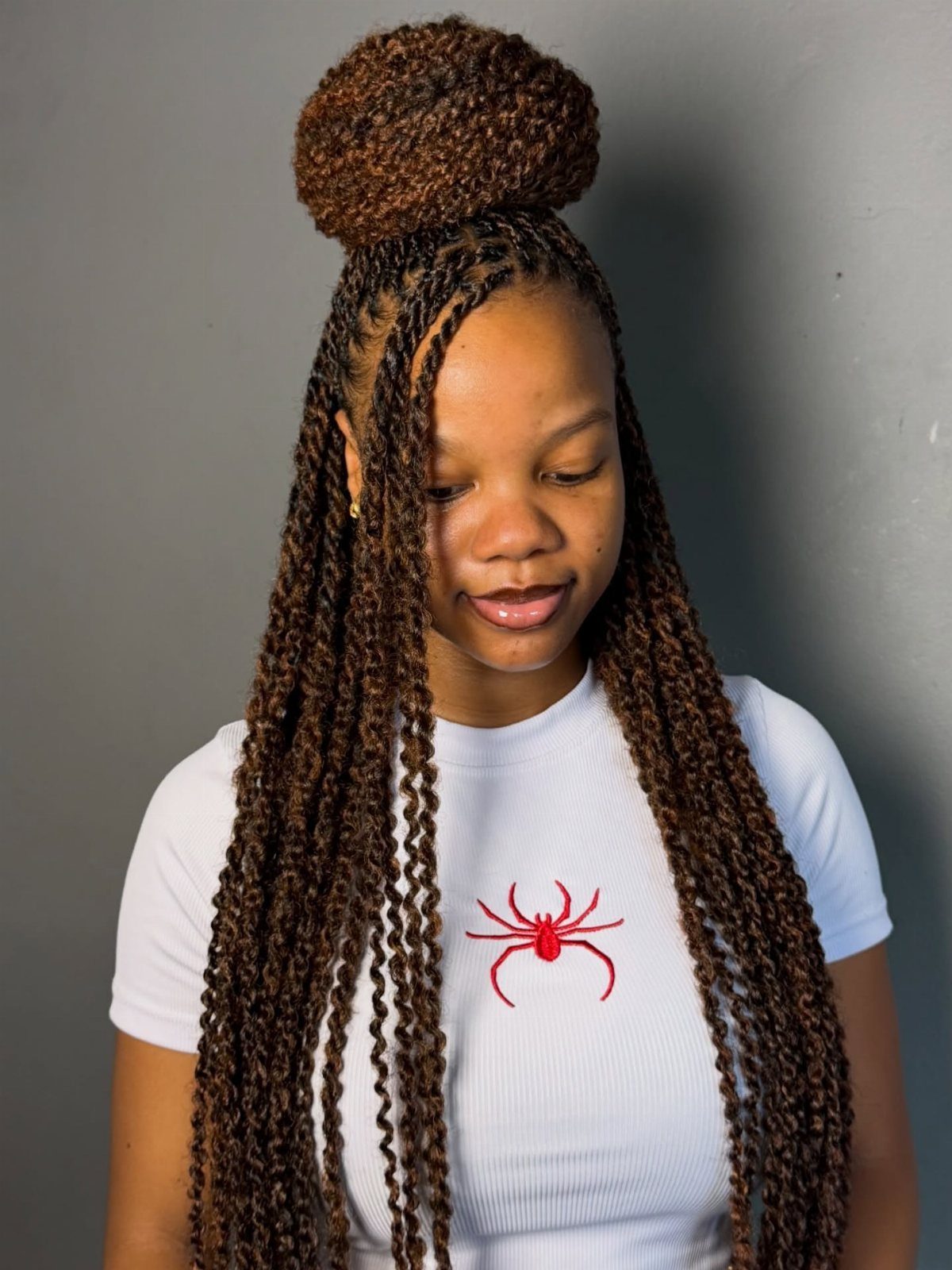 Two Strand Twist Natural Hair Women: 10 Style Ideas 5 Woman with long brown two-strand twists styled in a high bun and loose strands.