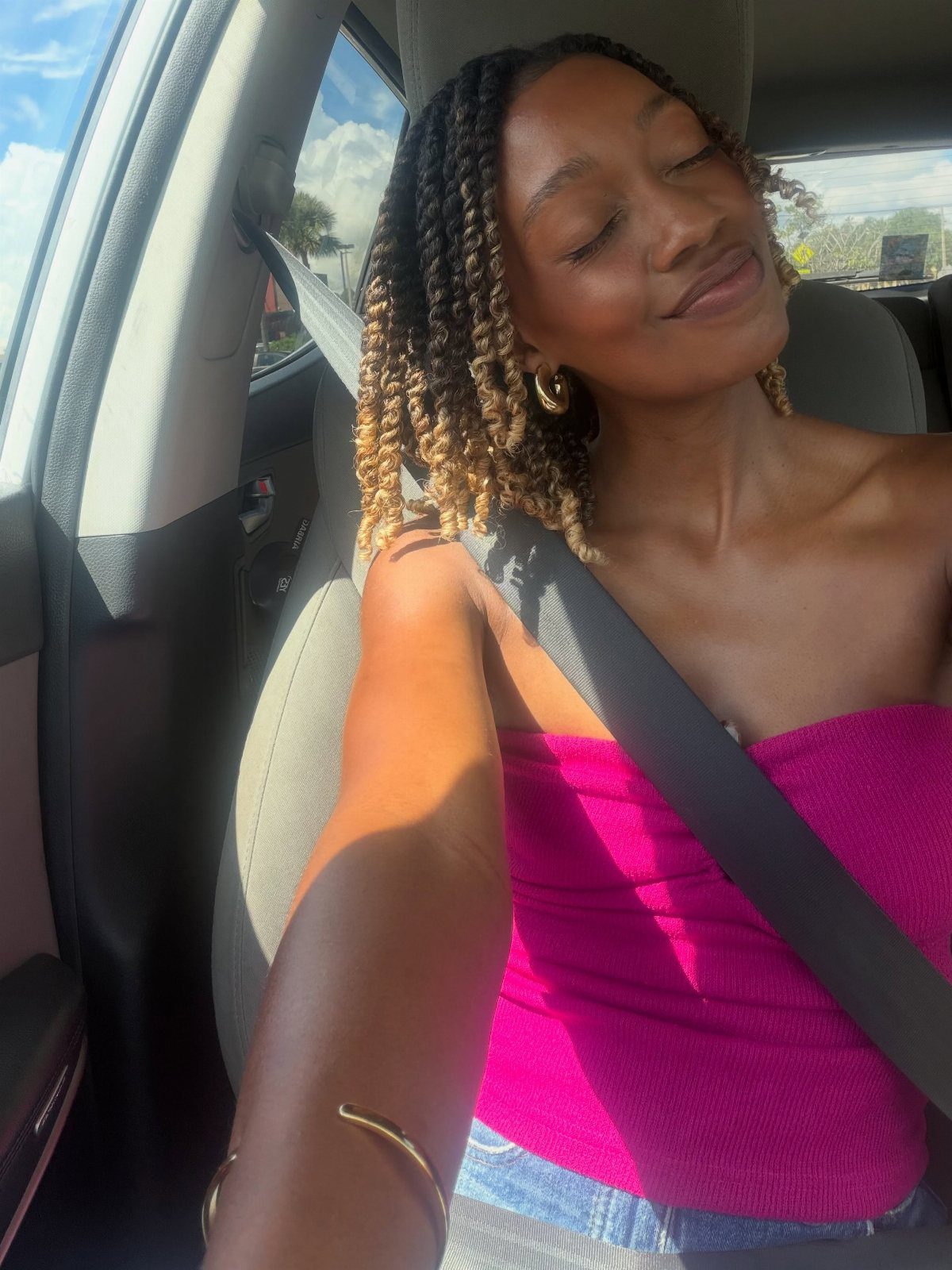 Two Strand Twist Natural Hair Women: 10 Style Ideas 7 Woman with blonde and brown two-strand twist hair smiling in a car