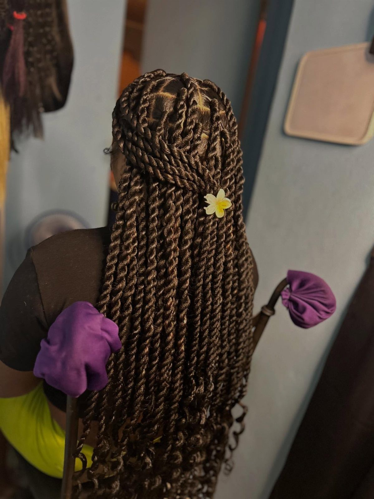 Two Strand Twist Natural Hair Women: 10 Style Ideas 8 Woman with long dark brown two-strand twists and a small white flower accessory.
