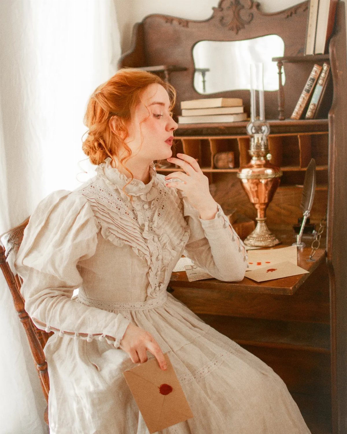 Victorian Era Sleeves: 6 Styles From Puffed to Bell 3 Woman in a beige Victorian dress with puffed shoulders sitting at a wooden desk.