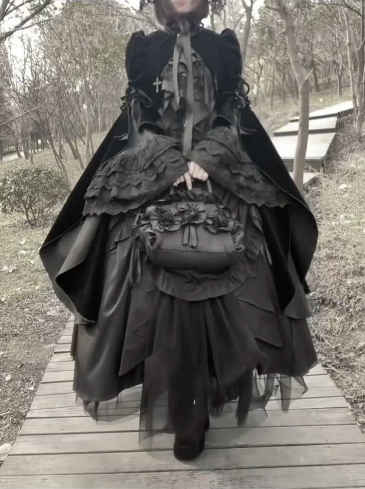 Victorian Era Sleeves: 6 Styles From Puffed to Bell 5 Person in gothic black dress with voluminous ruffled sleeves on wooden boardwalk