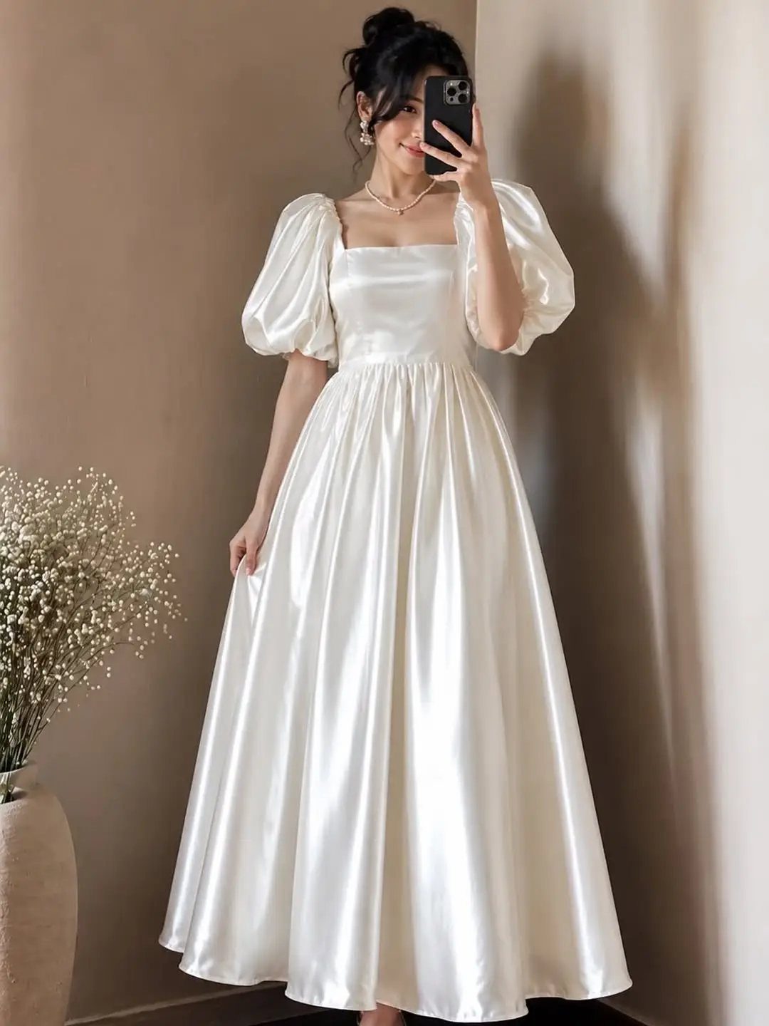 Woman in a cream satin vintage-style wedding dress with puff sleeves taking a selfie