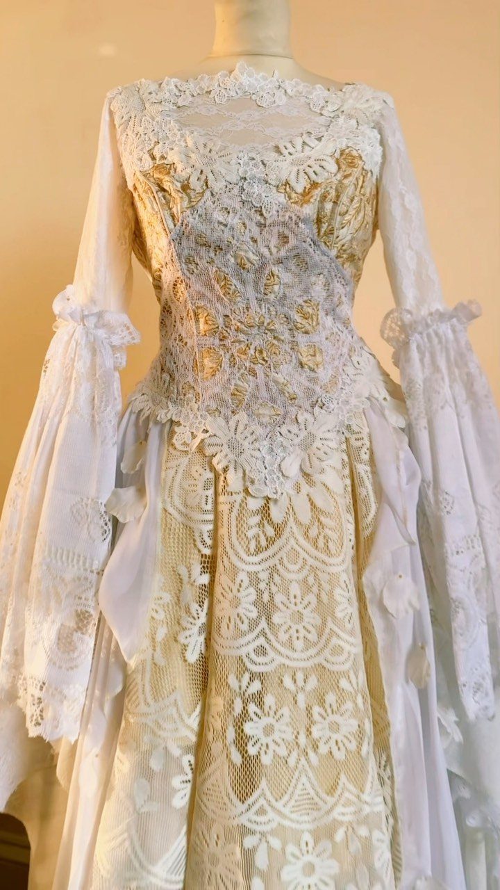 Vintage ivory wedding dress with gold accents and flowy lace bell sleeves.