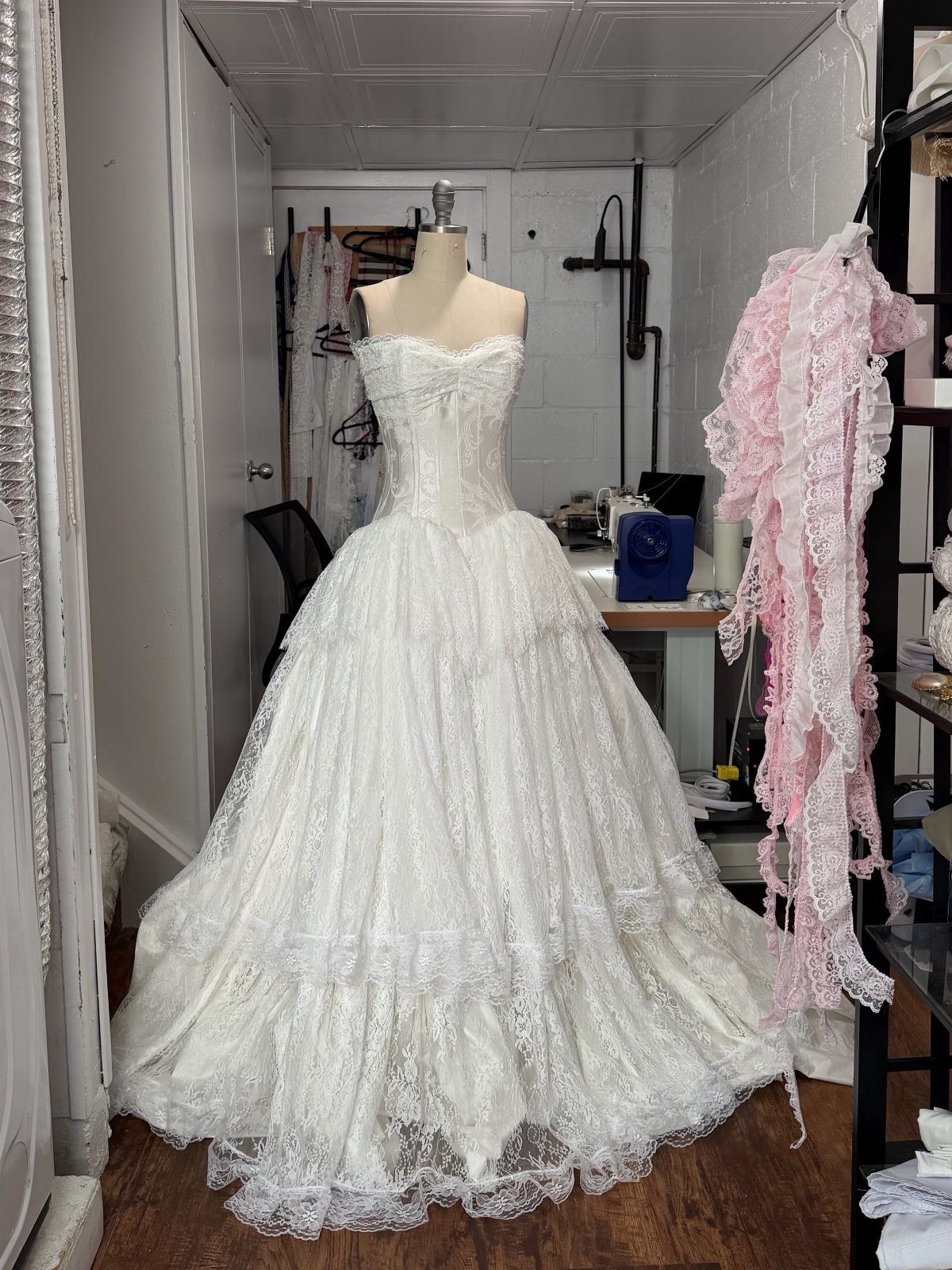 White strapless wedding dress with tiered lace skirt on a studio mannequin
