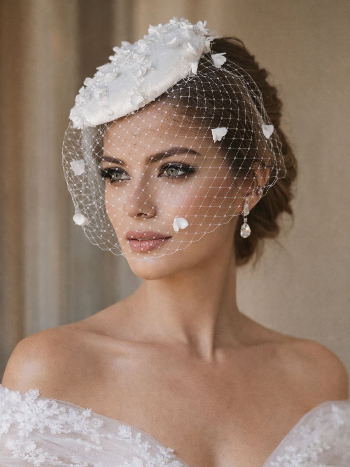 Woman wearing a white floral bridal headpiece with a delicate birdcage veil.