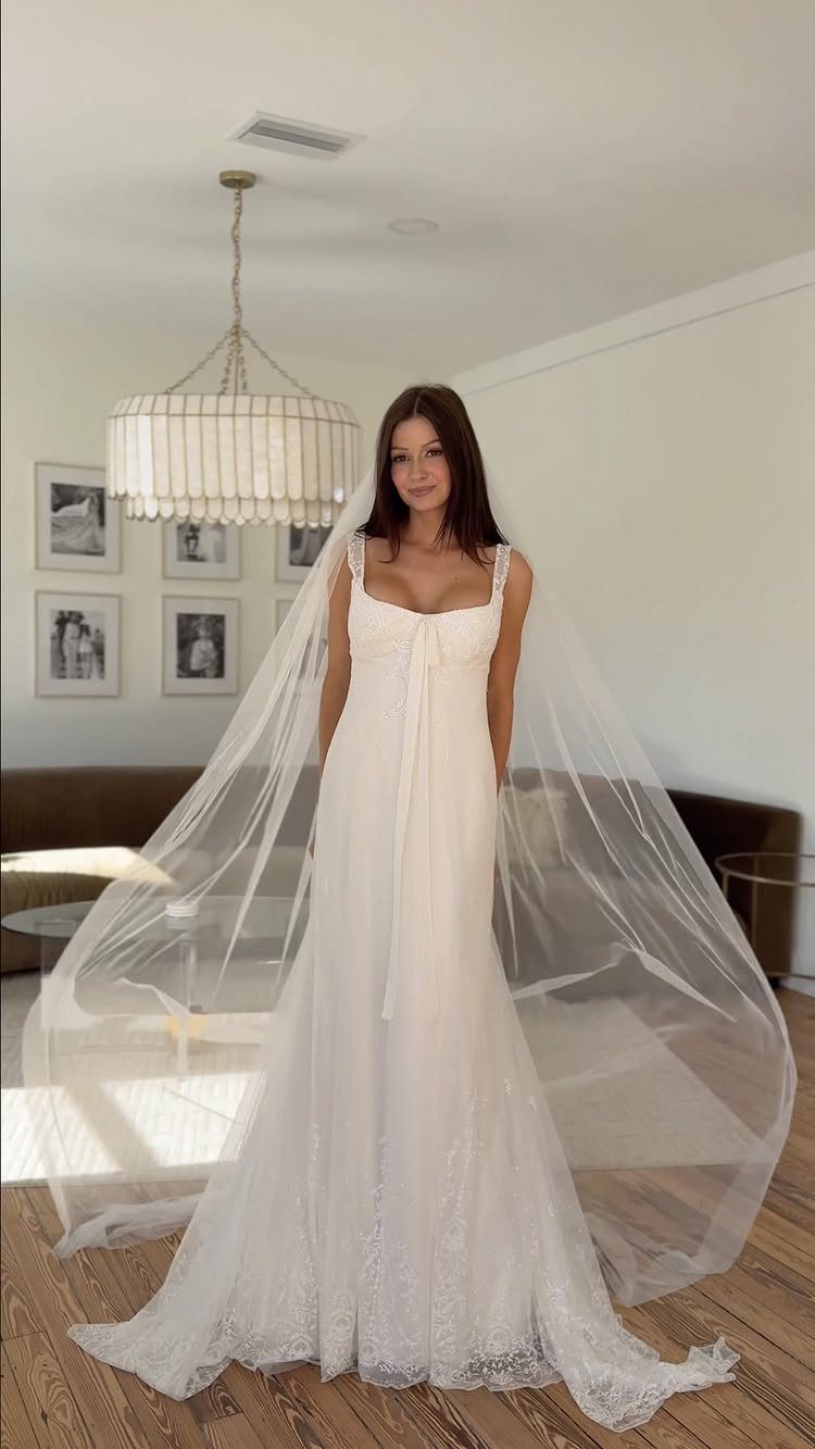 Woman in a white vintage-inspired floral lace wedding dress with a long veil.