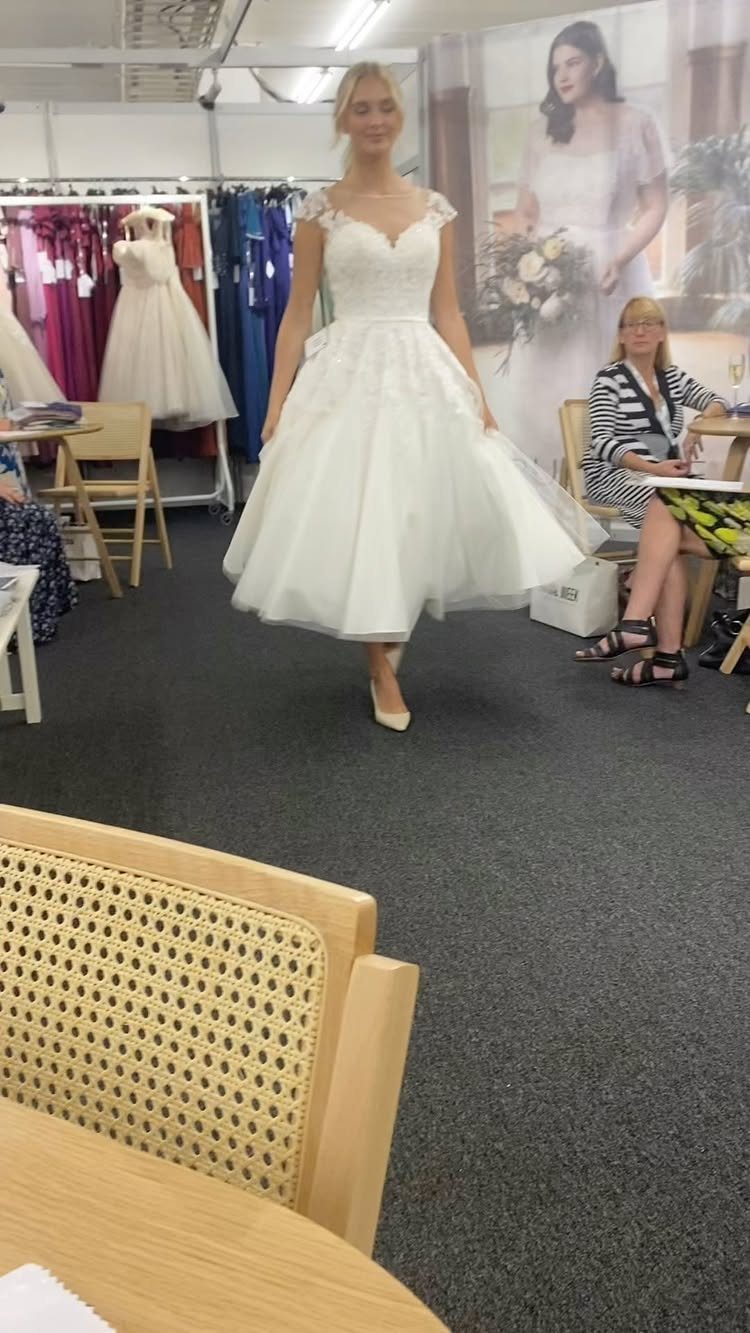 Woman wearing a white tea-length vintage style wedding dress in a bridal shop