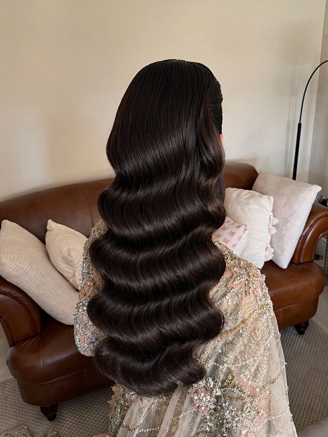 Long dark brown hair styled in glossy, structured vintage S-waves from behind.