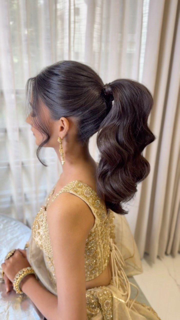 Woman with a high voluminous ponytail and structured waves wearing a gold dress