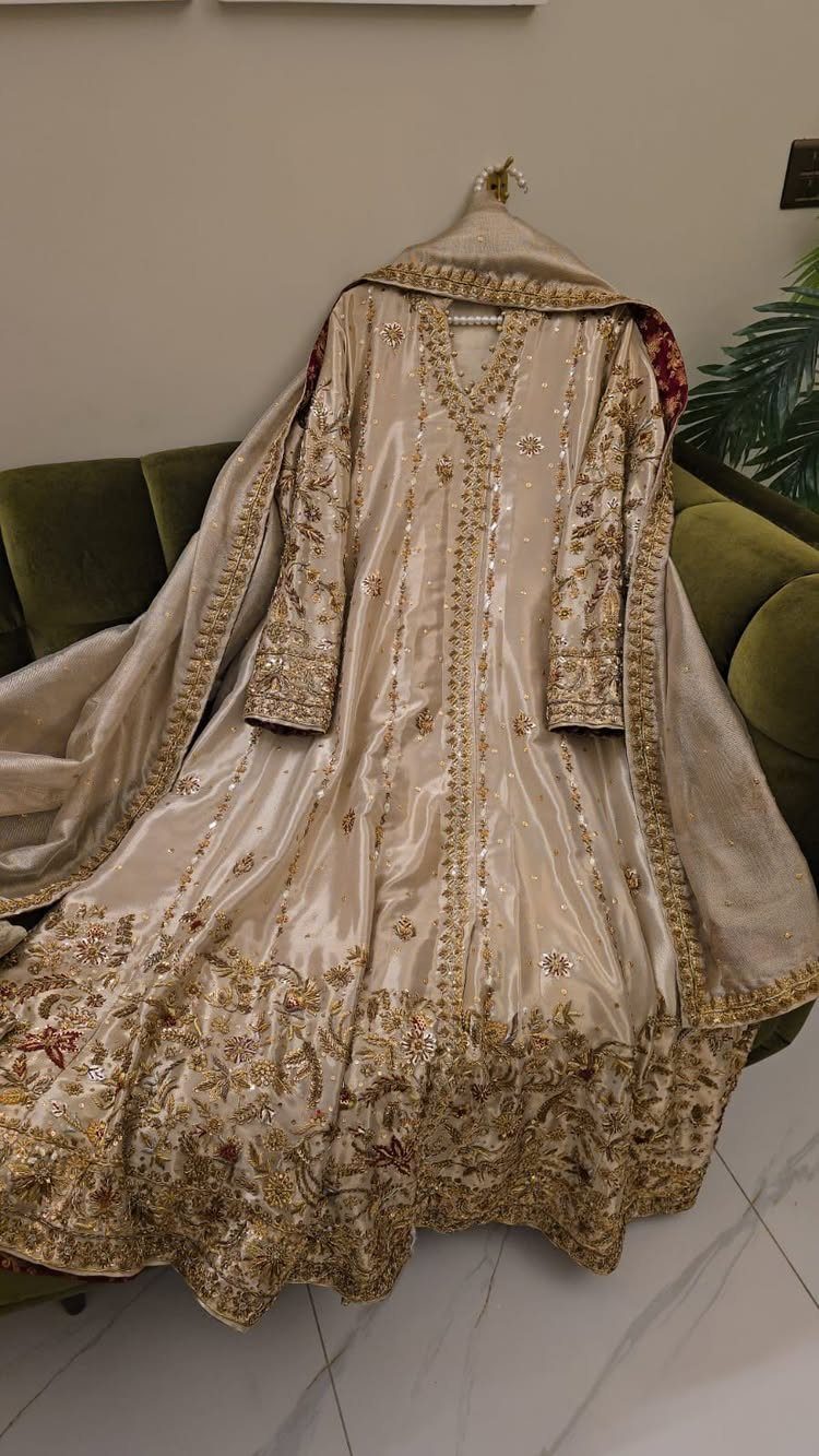 Wedding Dresses Off White: 9 Ideas for Every Bride 4 Off-white bridal lehenga with intricate gold embroidery hanging over a green sofa