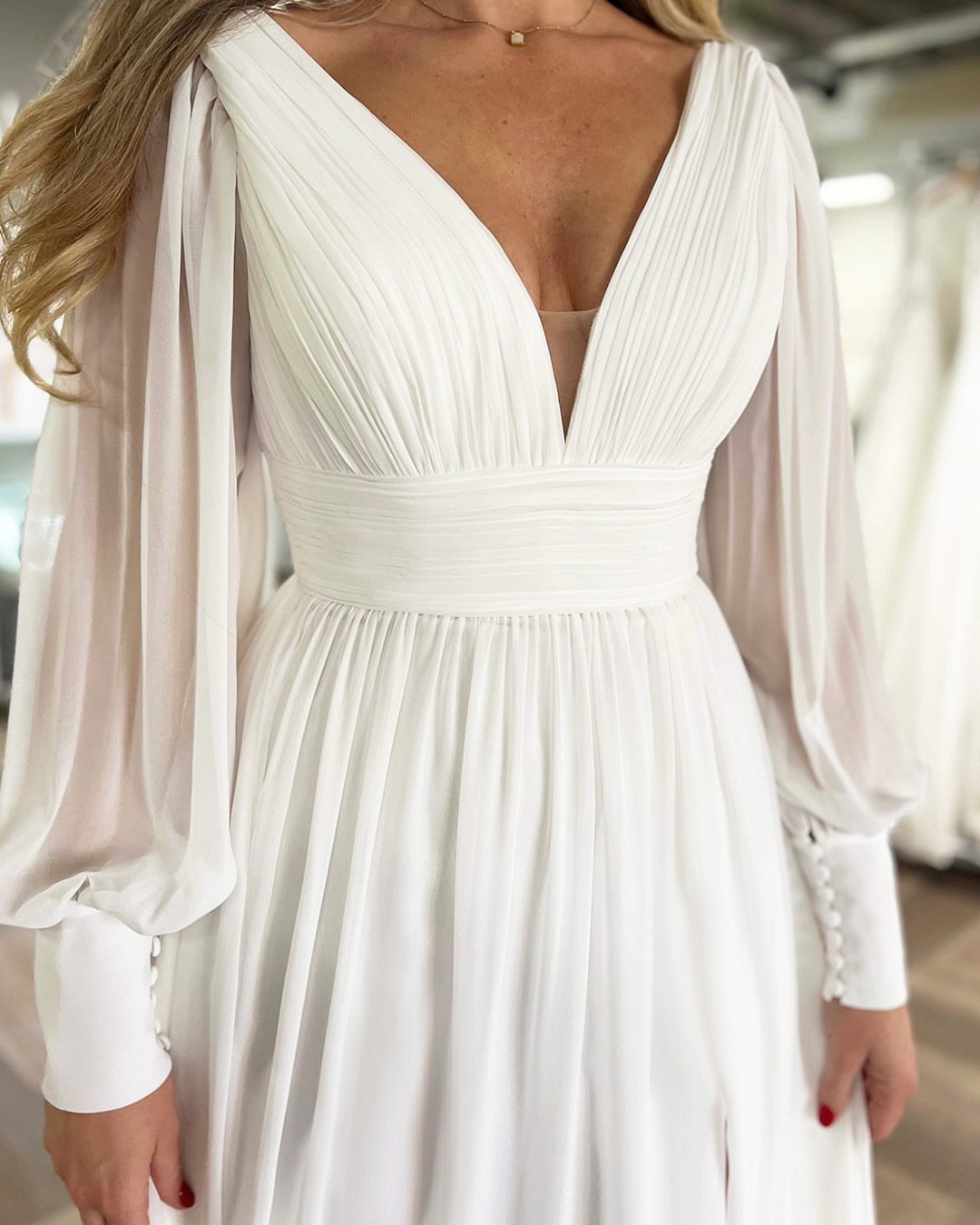 Wedding Dresses Off White: 9 Ideas for Every Bride 7 Off-white wedding dress with V-neck, pleated bodice, and long sheer bishop sleeves.