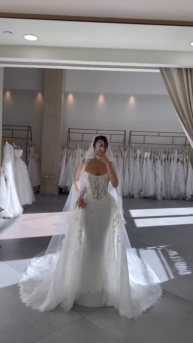 Wedding Dresses Off White: 9 Ideas for Every Bride 1 Woman wearing a strapless off-white lace bridal gown and veil in a boutique.