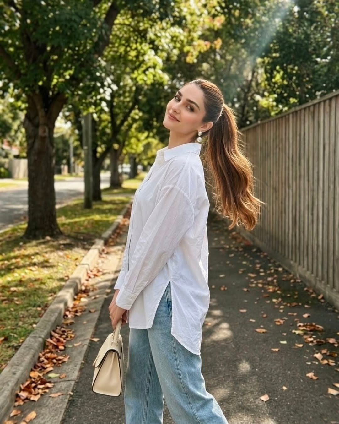 Woman wearing an oversized white button-down shirt and light blue jeans outdoors