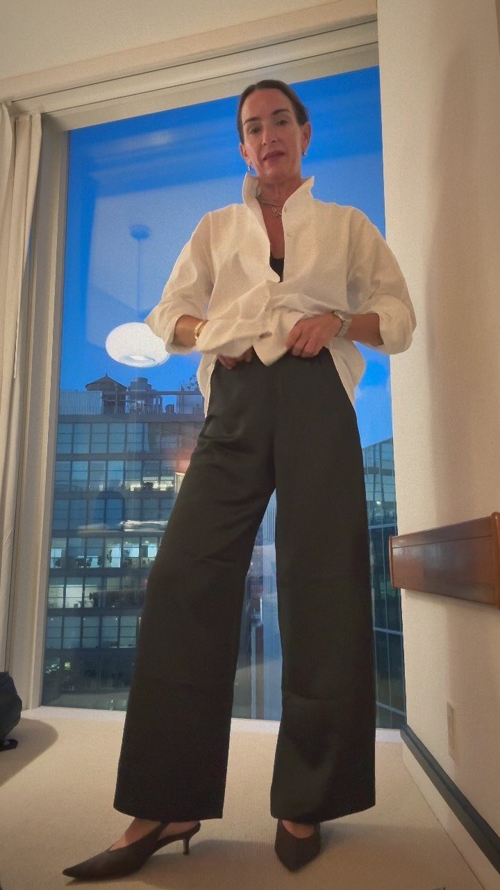 Woman wearing a knotted white shirt and wide-leg black tailored trousers with heels.