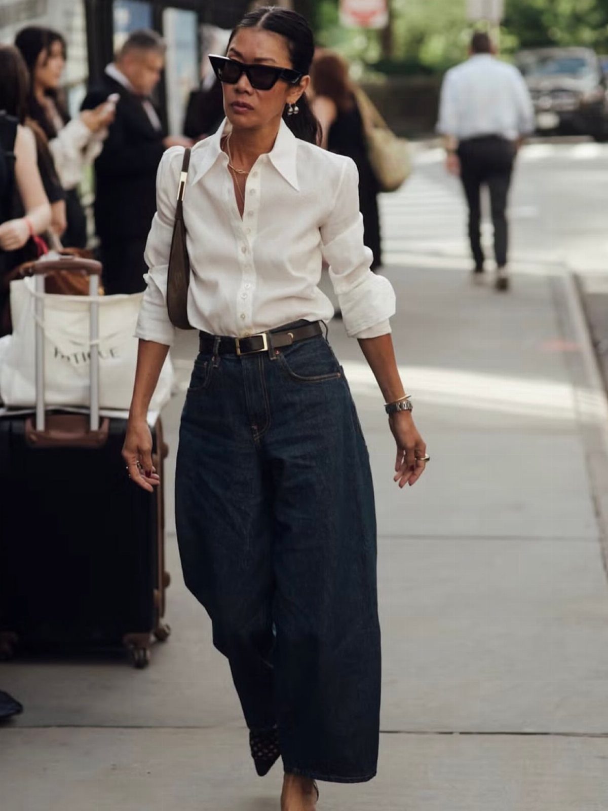 Woman wearing a white button-down shirt tucked into a long dark denim skirt.