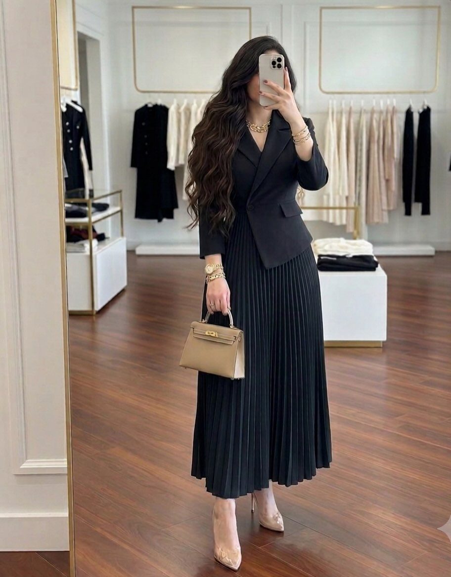 14 Women Skirt Outfits for Every Season and Occasion 3 Woman wearing a black blazer and black pleated full skirt with nude heels.