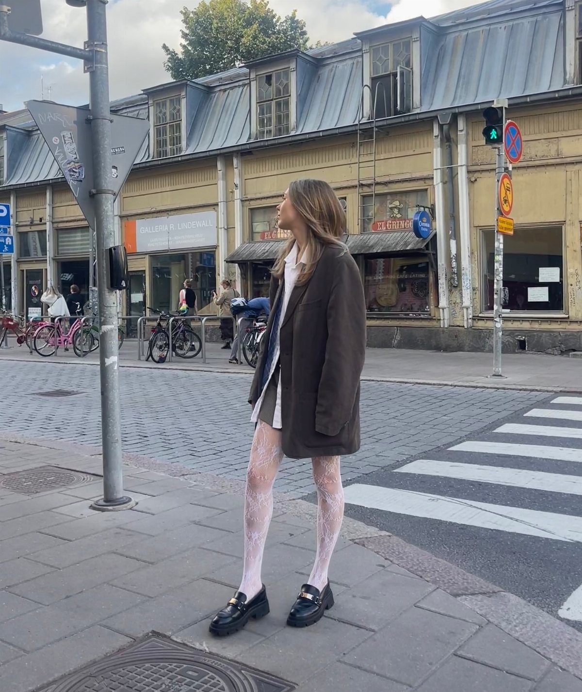 14 Women Skirt Outfits for Every Season and Occasion 12 Woman wearing a white mini skirt, olive blazer, and black loafers on a sidewalk
